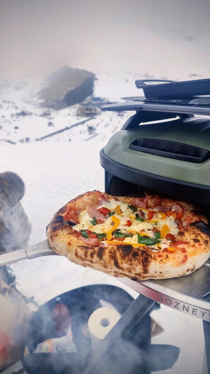 Frische Pizza aus dem Ofen im Schnee mit Bergpanorama